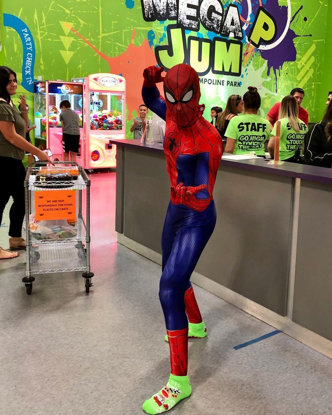 Spider-Man poses inside Mega Jump. Wearing red and blue costume and neon green shoes, he flexes his arm.
