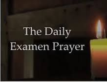A candle is lit in front of a sign that says `` the daily examen prayer ''.