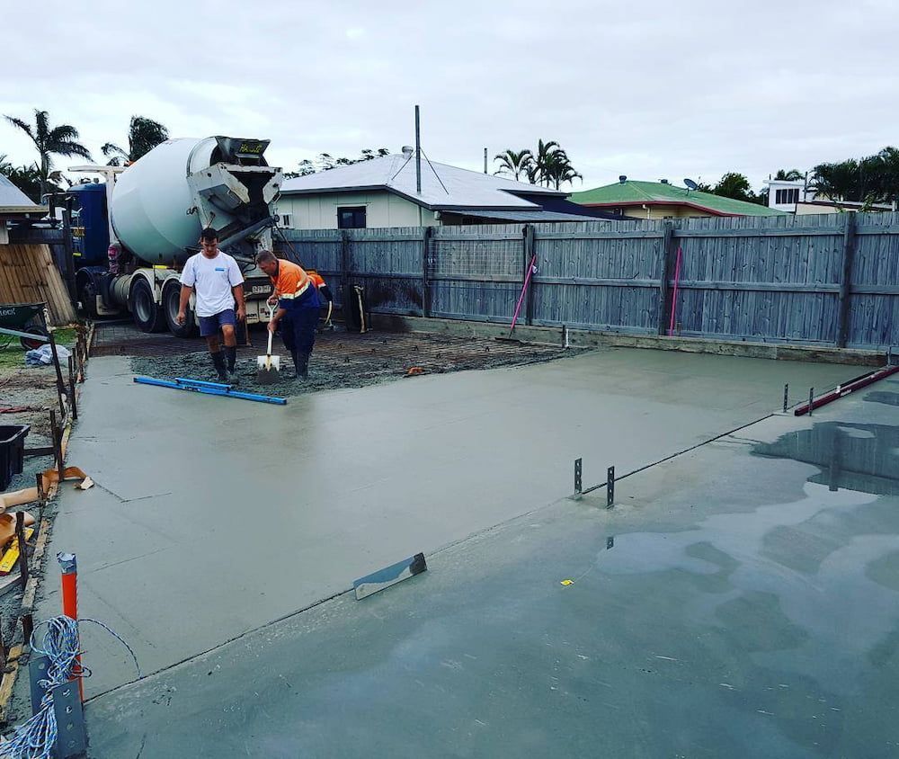 Two Men Are Working on a Concrete Floor in Front of a Mixer Truck — TJ Concreting in Ballina, NSW