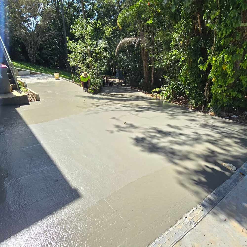 A Man is Walking Down a Concrete Driveway Surrounded by Trees — TJ Concreting in Lismore, NSW