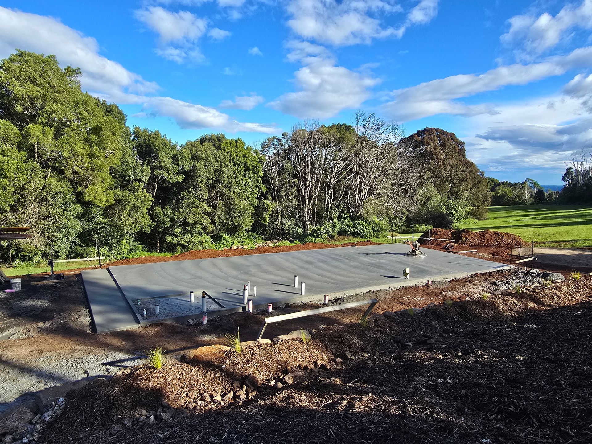 A Close Up of a Concrete Driveway With Trees in the Background — TJ Concreting in Federal, NSW 