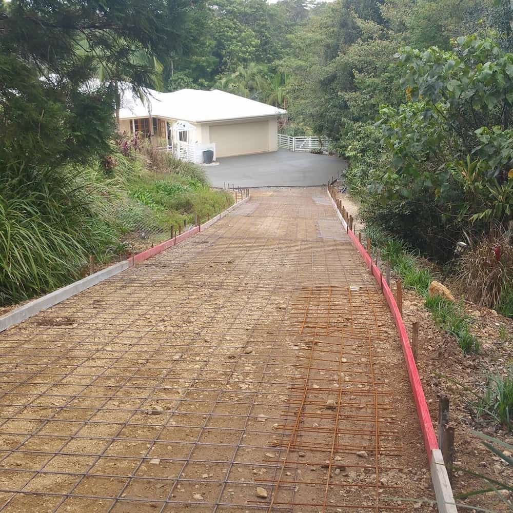 A Dirt Road Leading to a House Surrounded by Trees and Bushes — TJ Concreting in Ballina, NSW