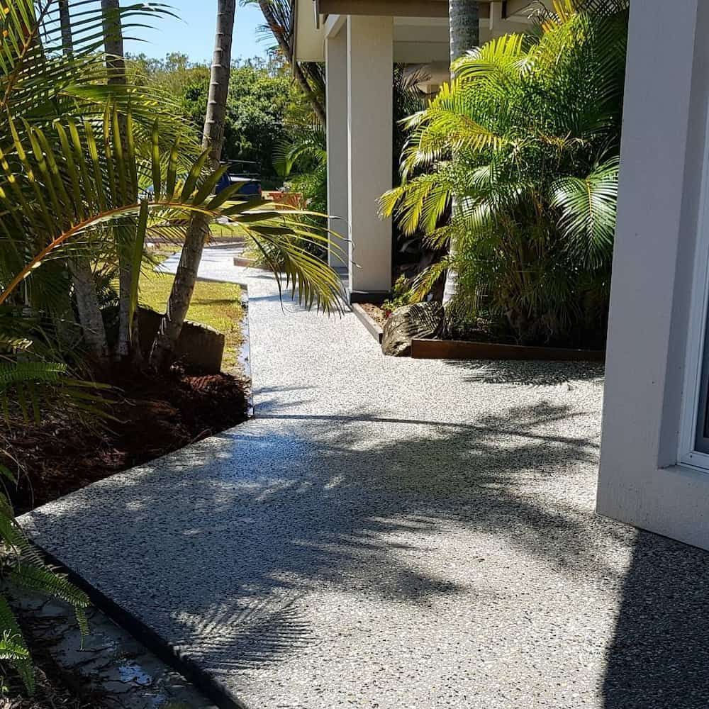 A Concrete Walkway Leading to a House Surrounded by Palm Trees — TJ Concreting in Myocum, NSW