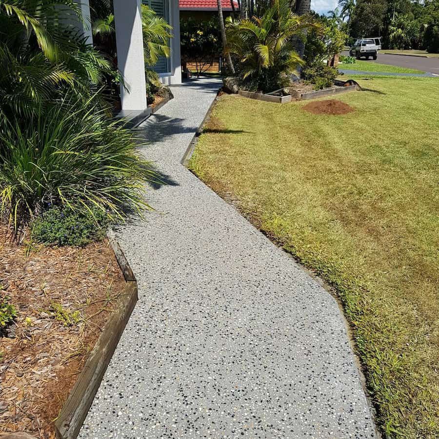 A Concrete Walkway Leading to a House Next to a Lush Green Lawn — TJ Concreting in Myocum, NSW