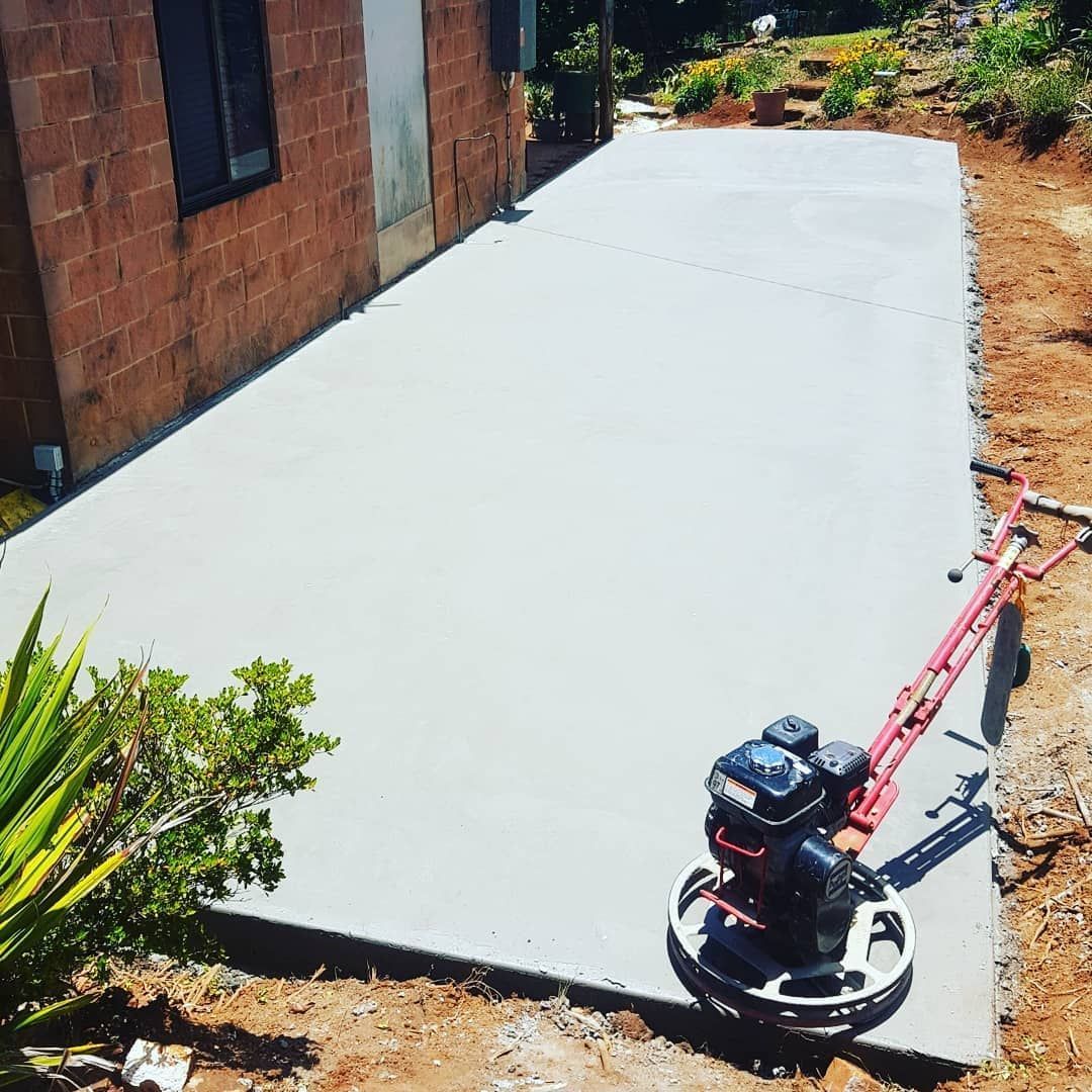 A Concrete Grinder is Sitting on Top of a Concrete Driveway — TJ Concreting in Federal, NSW