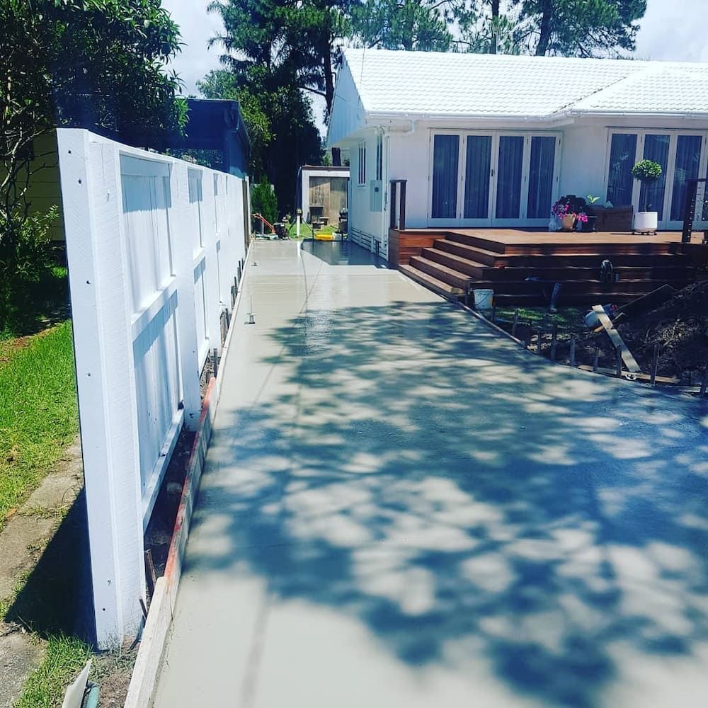 A White House With a Concrete Driveway Leading to It — TJ Concreting in Lismore, NSW