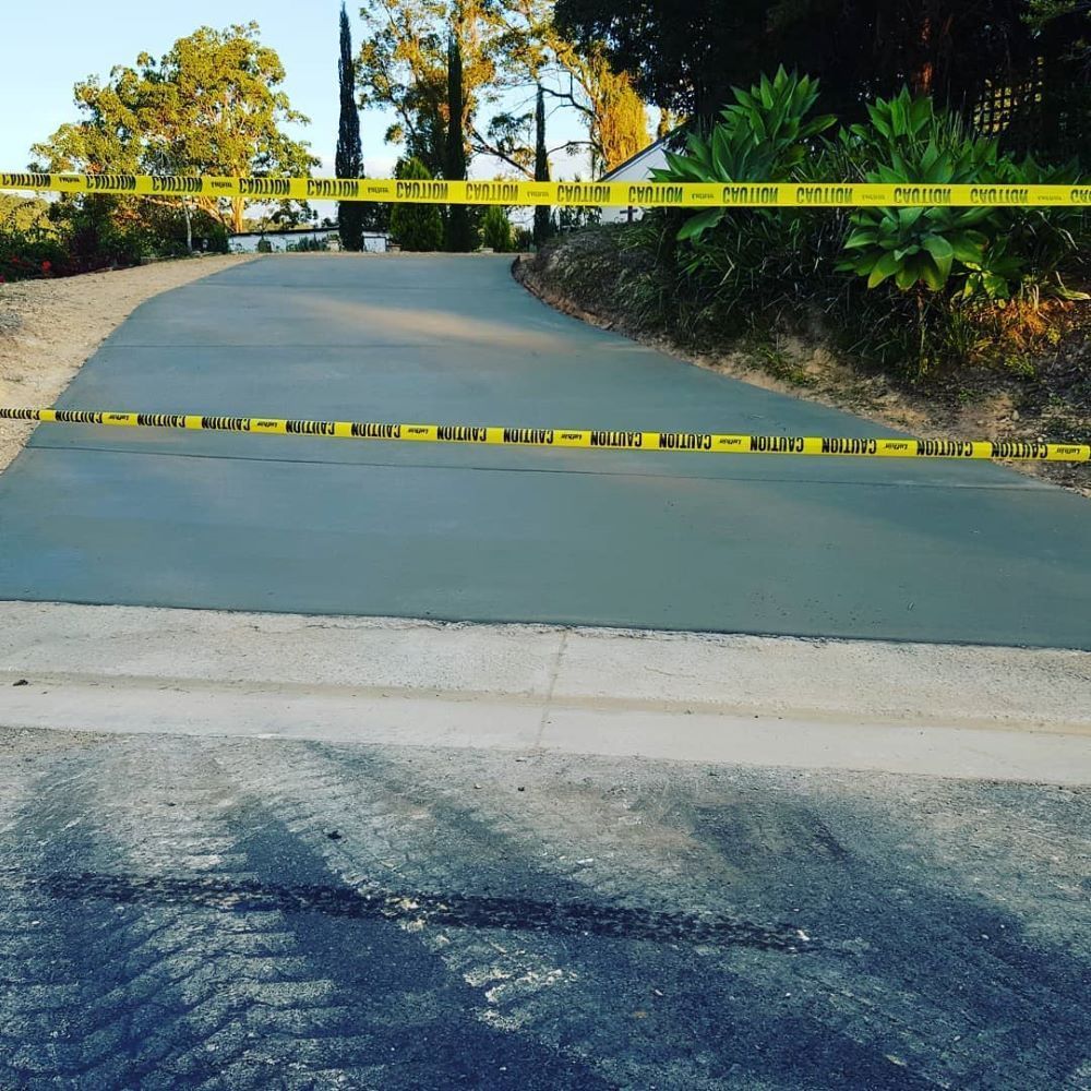 A Concrete Driveway With Yellow Tape on It — TJ Concreting in Myocum, NSW