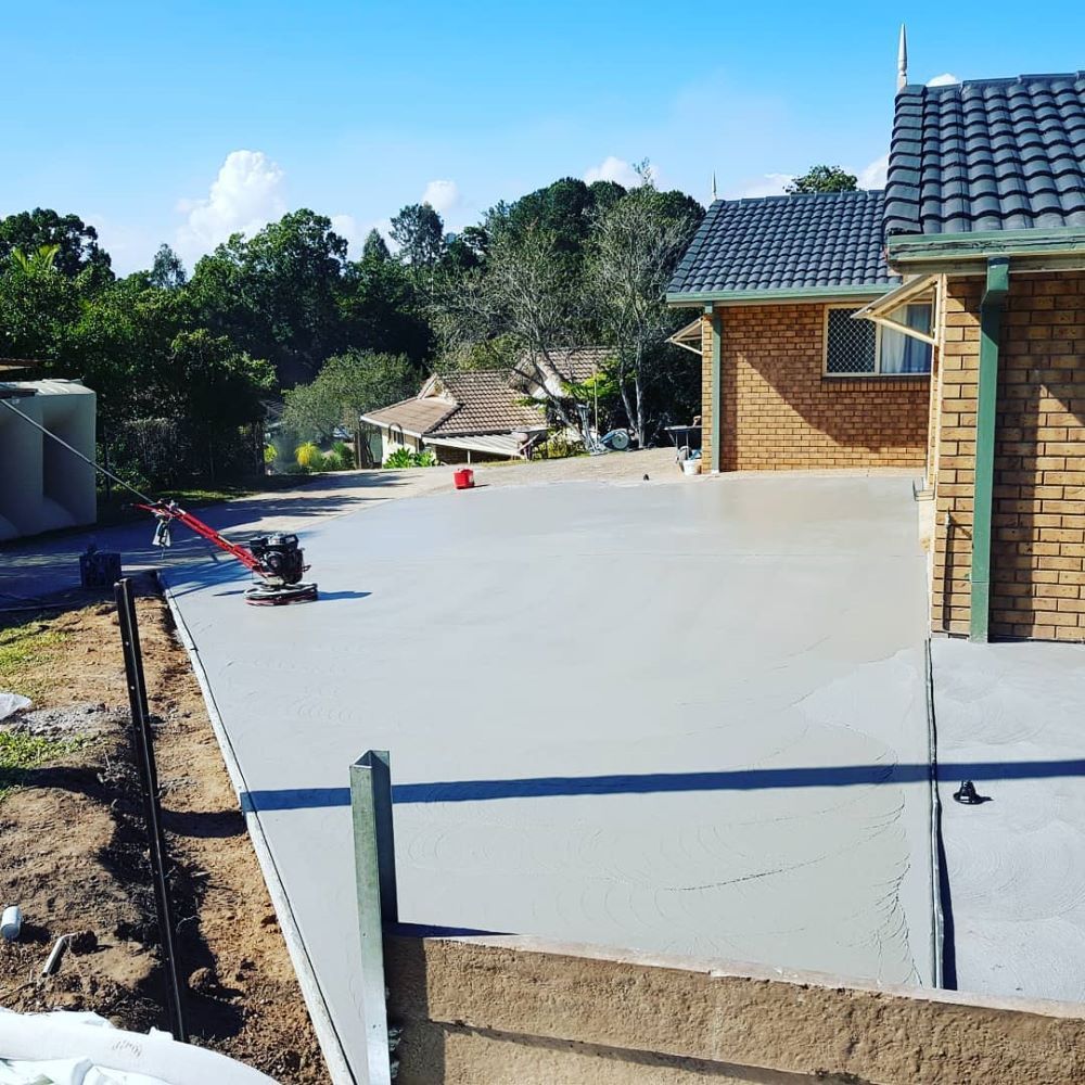 A Brick House With a Concrete Driveway in Front of It — TJ Concreting in Bangalow, NSW 