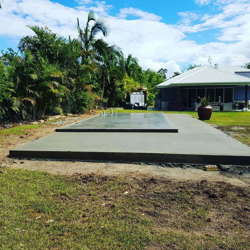 A Large Concrete Slab is Sitting in the Grass in Front of a House — TJ Concreting in Murwillumbah, NSW