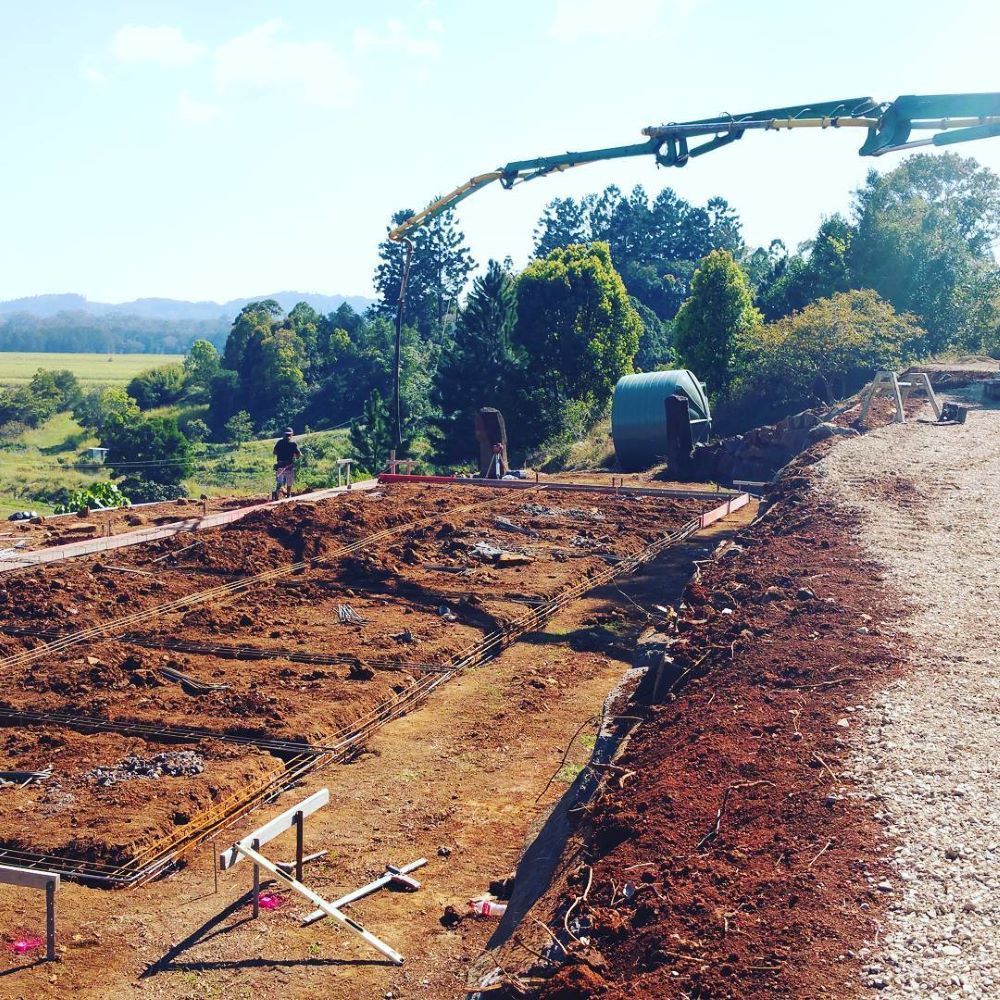 A Concrete Pump is Pouring Concrete on a Dirt Road — TJ Concreting in Murwillumbah, NSW