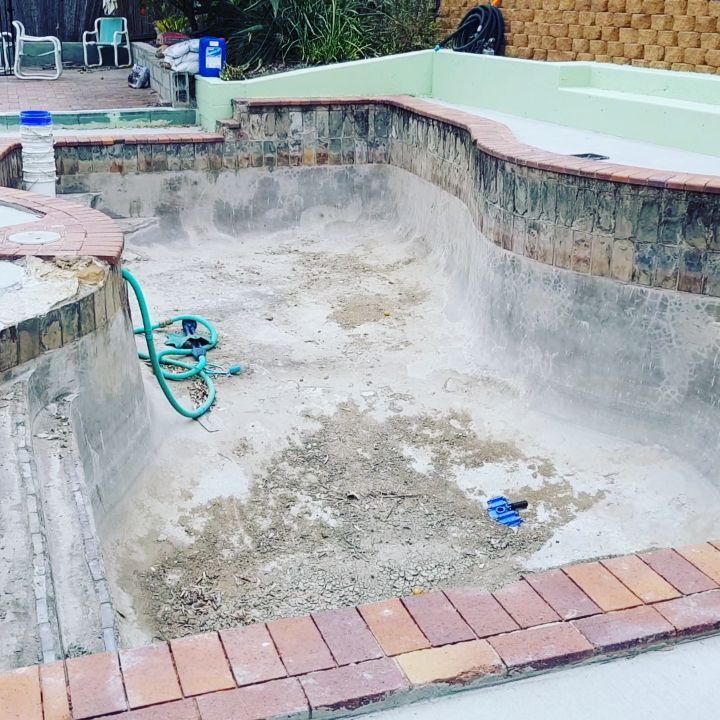 An Empty Swimming Pool With a Hose in It — TJ Concreting in Myocum, NSW