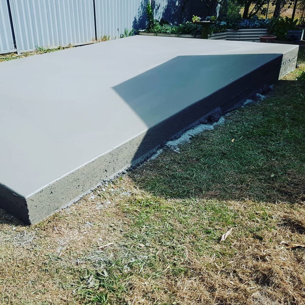 A Concrete Walkway is Sitting on Top of a Lush Green Field — TJ Concreting in Myocum, NSW