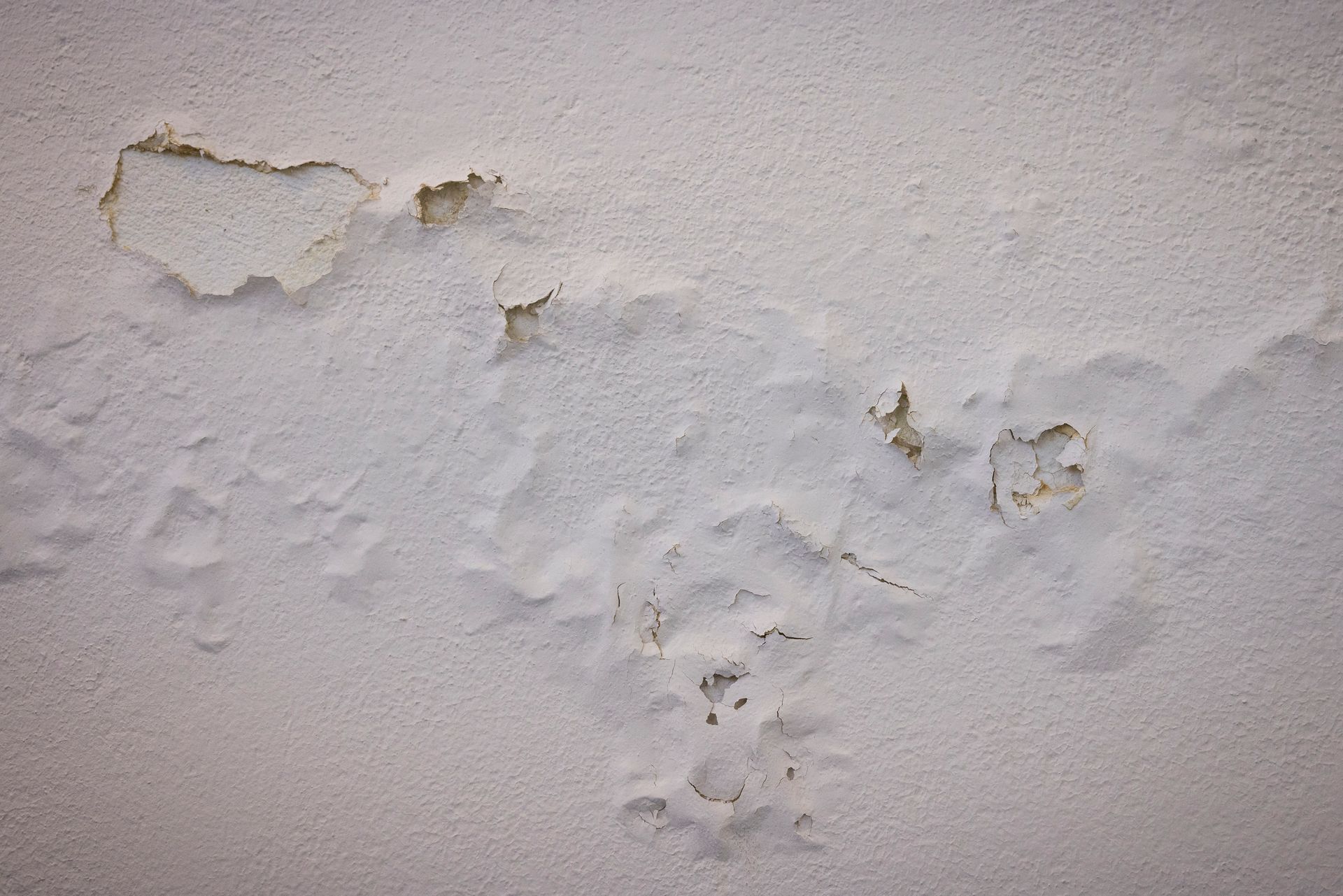A close up of a white wall with peeling paint.