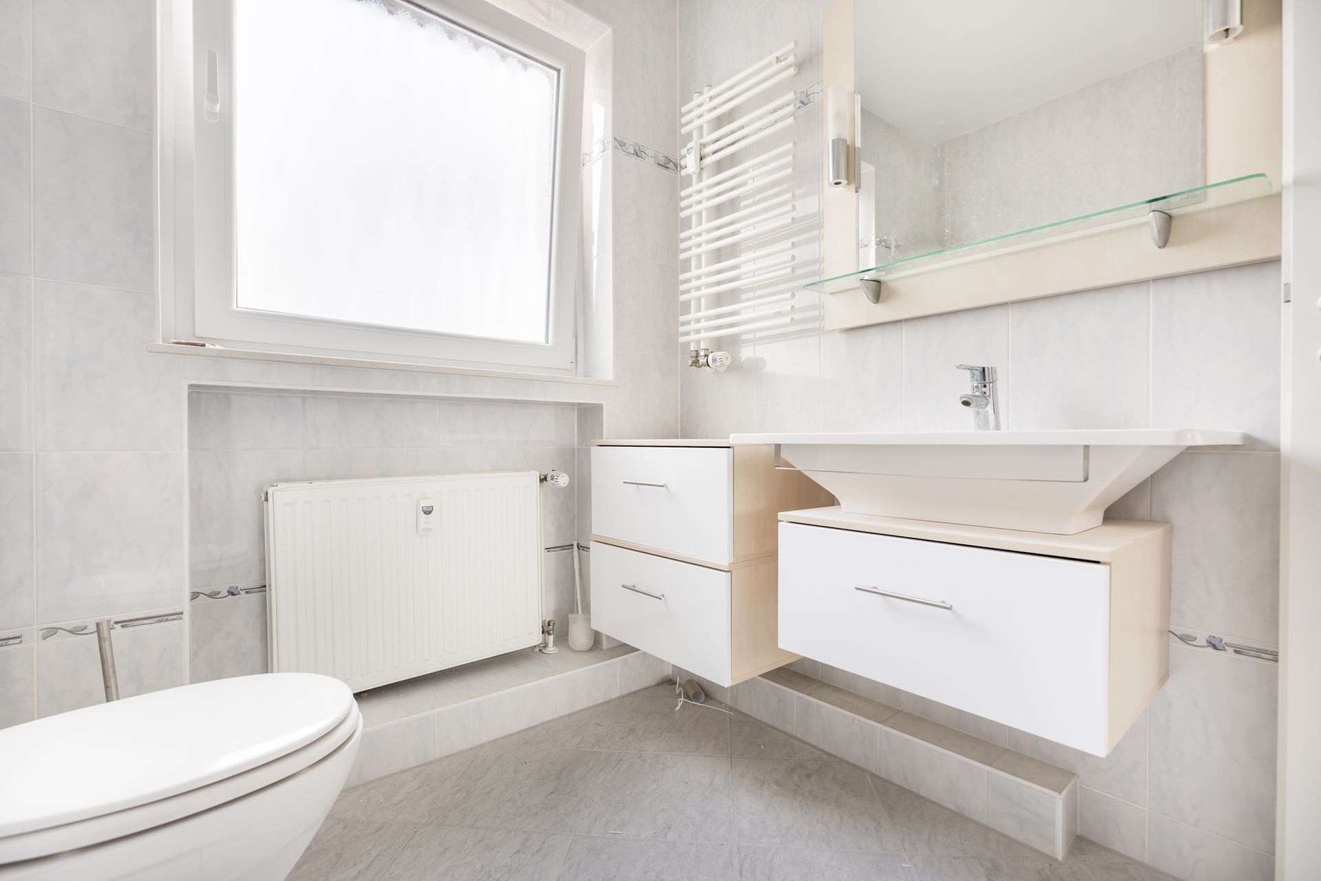 A bathroom with a toilet , sink , mirror and radiator.