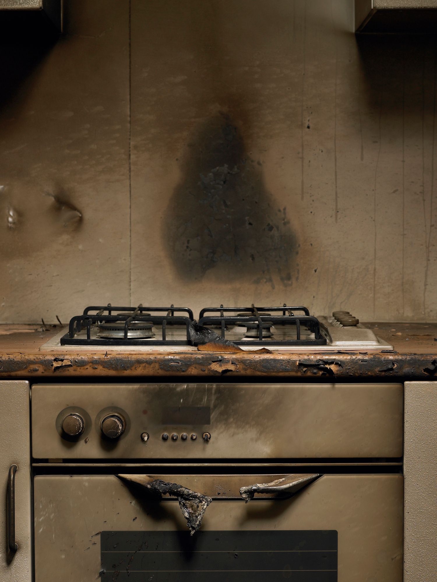 A stove with a shadow of a person on the wall behind it