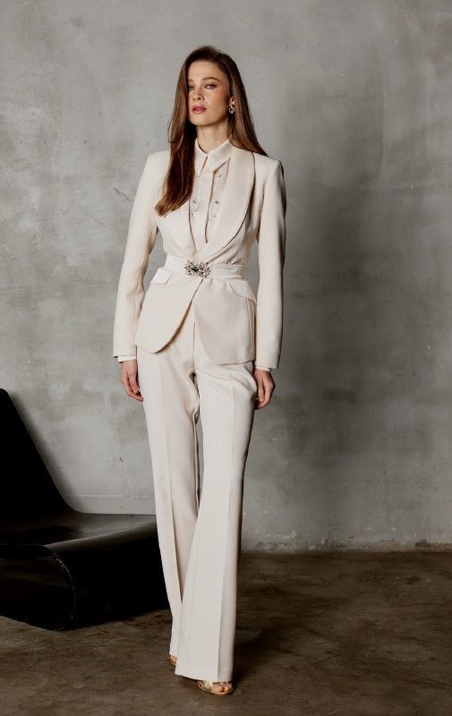 Una donna indossa un abito bianco ed è in piedi accanto a una sedia.