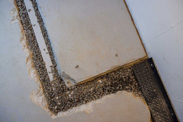 Section of concrete floor showing gravel fill and a drainage system.