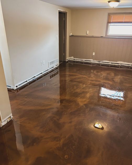 A living room with a brown metallic floor and a window.