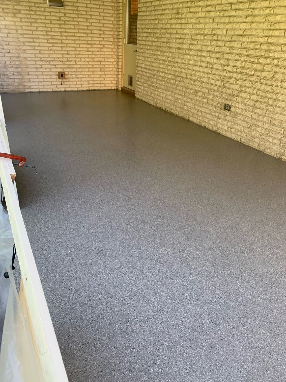 A garage with a concrete floor and a brick wall.