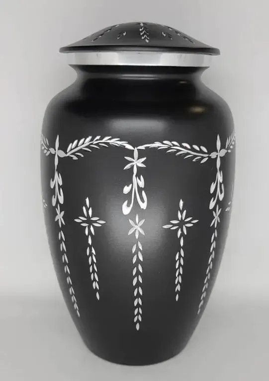 A black vase with white flowers and leaves on it