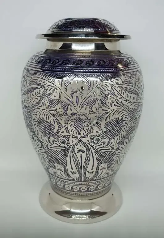 A silver urn with a floral design on it is sitting on a table.