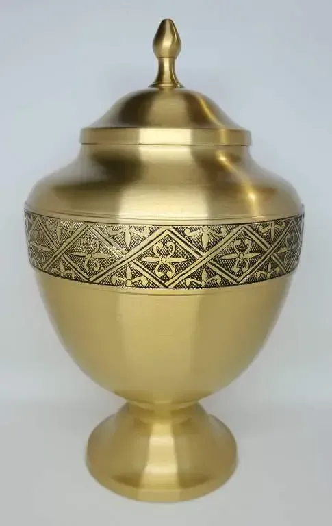 A brass vase with a lid and a pattern on it