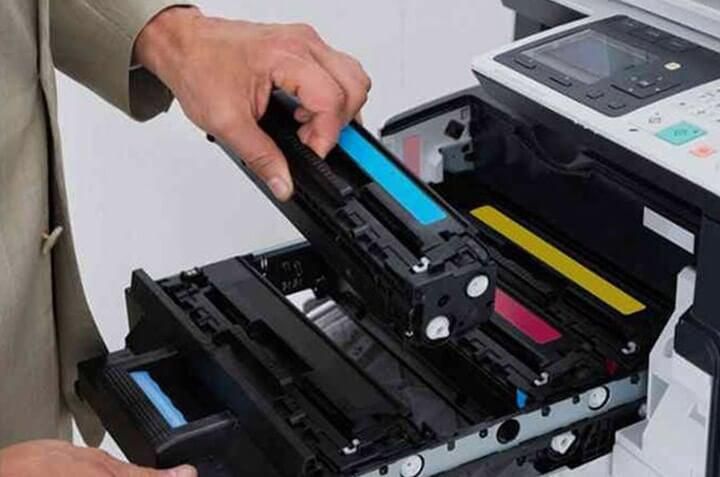 Una persona está sacando un cartucho azul de una impresora