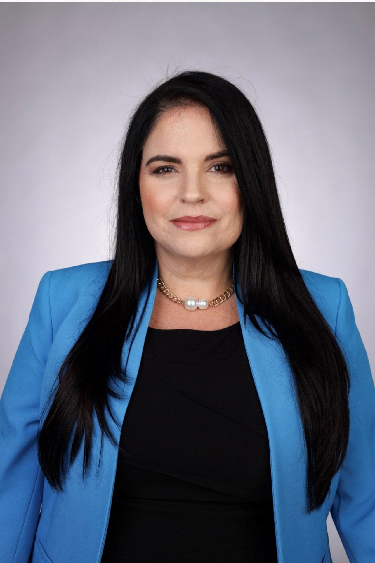 A woman with long black hair is wearing a blue jacket and a black shirt.