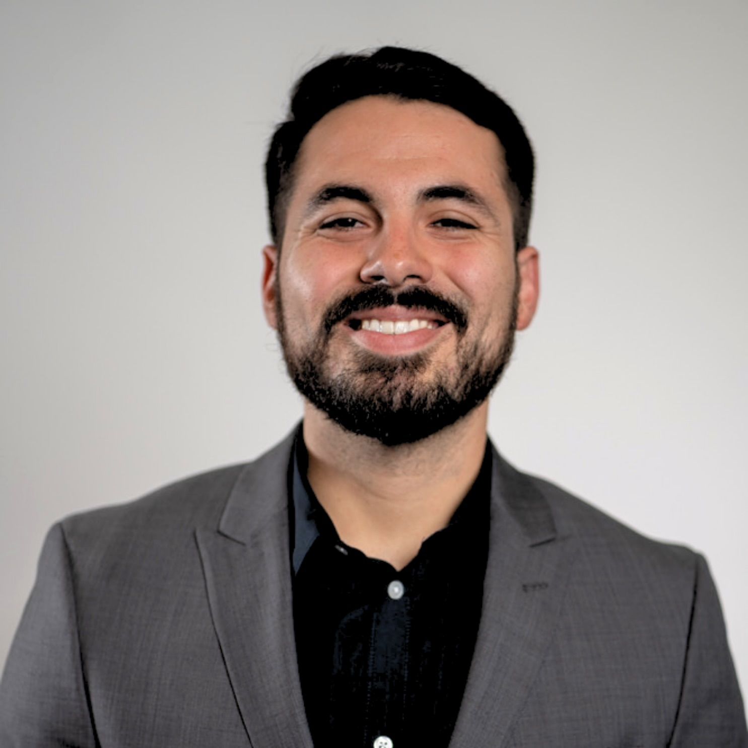 A man with a beard is wearing a suit and smiling