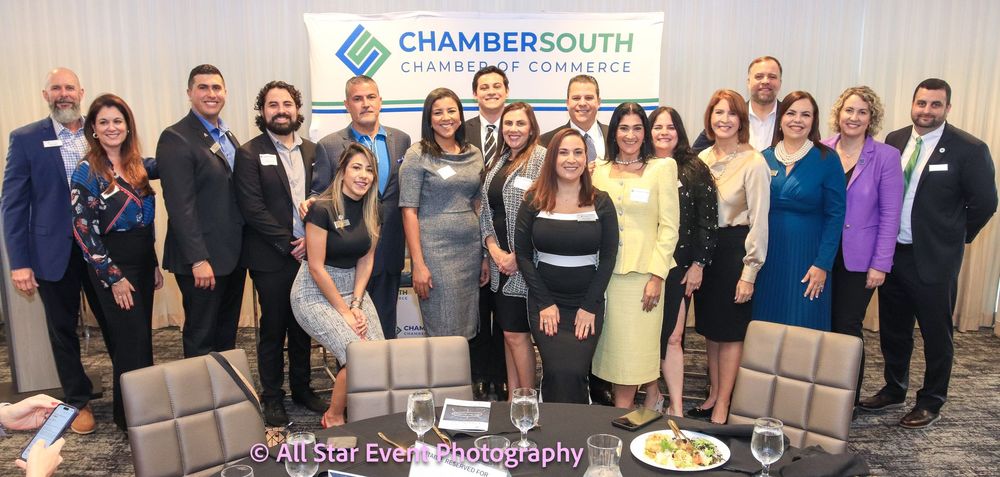 A group of people are posing for a picture in front of a chambersouth sign.