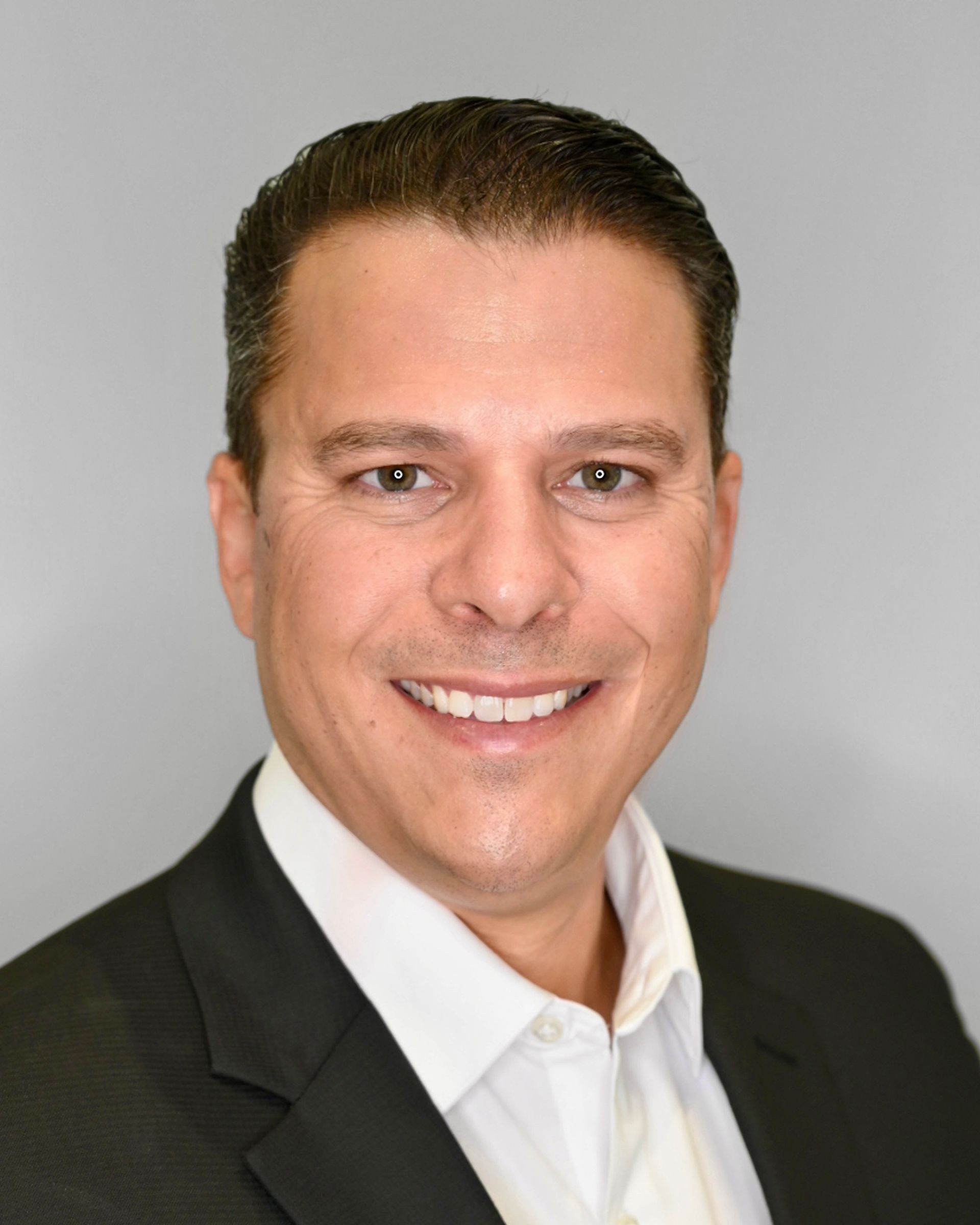 A man in a suit and white shirt is smiling for the camera