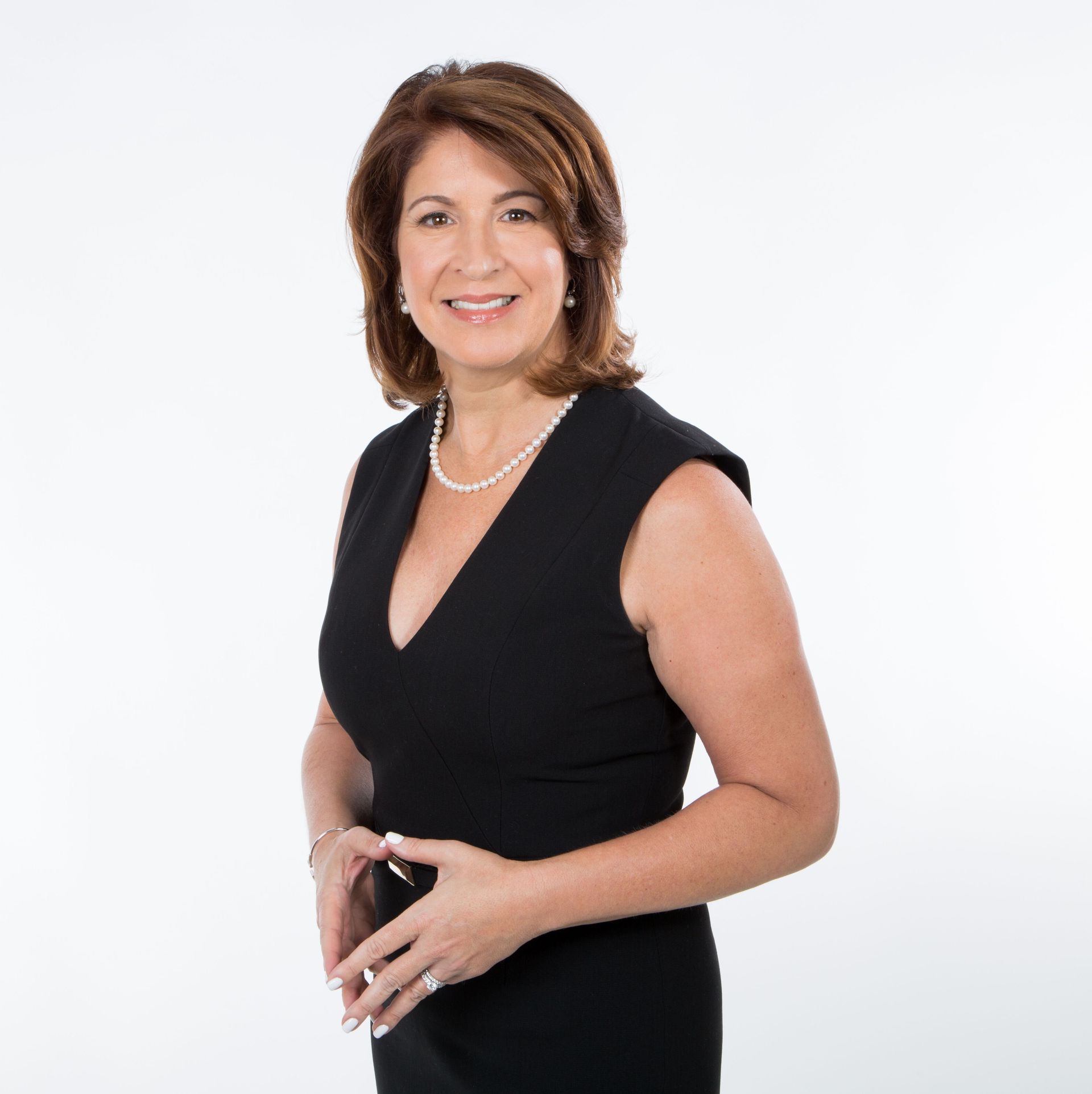 A woman is wearing a black dress and a pearl necklace.