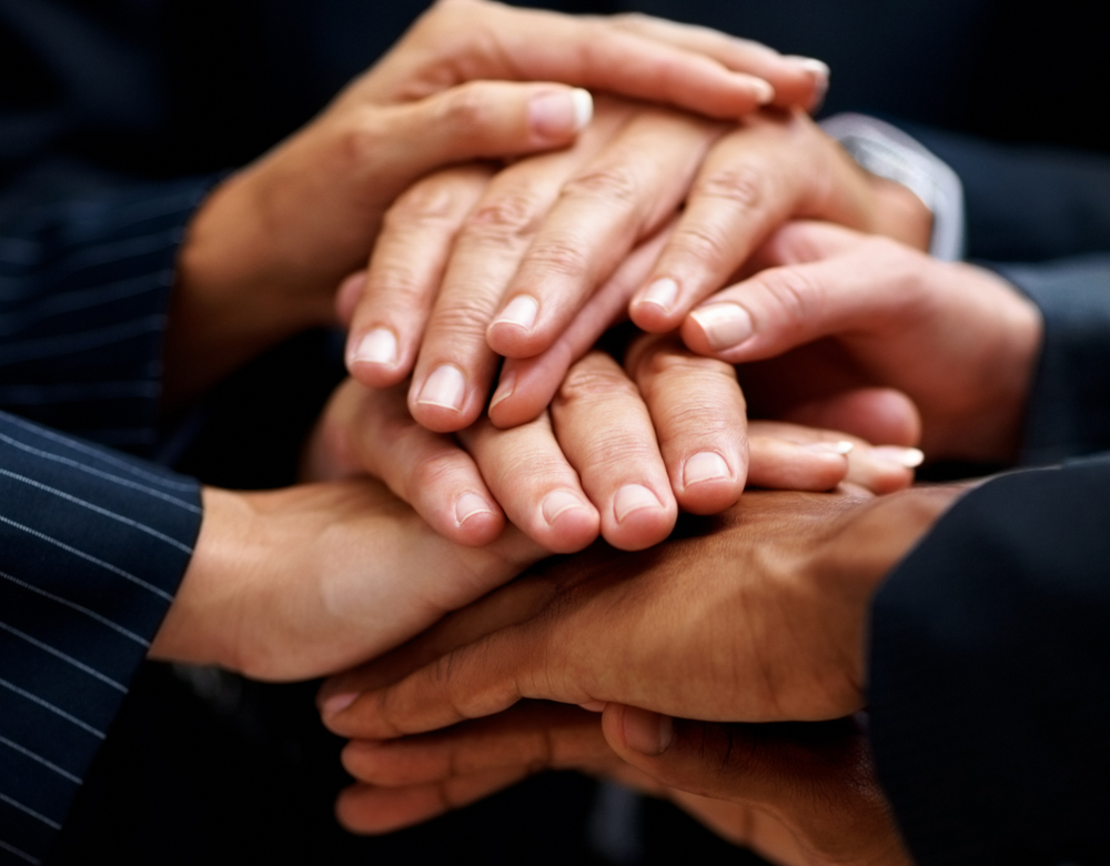 A group of people are putting their hands together