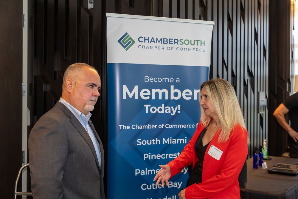 A man and a woman are standing in front of a sign that says become a member today.