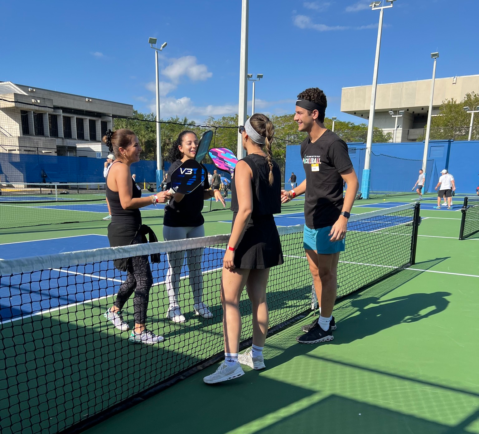 A group of people standing on a tennis court talking to each other