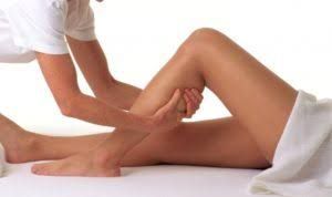 Un masajista profesional realiza un masaje de tejido profundo en el músculo de la pantorrilla