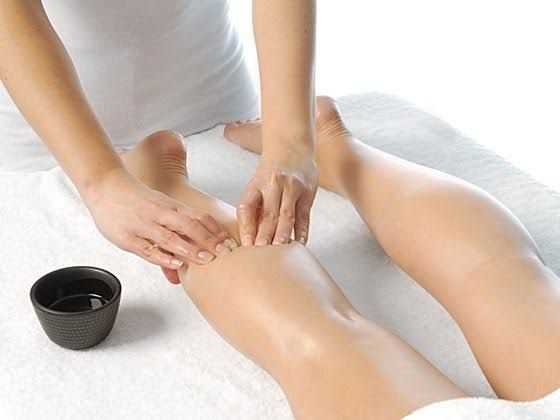 Un masajista aplica aceite en la parte inferior de la pierna de una persona