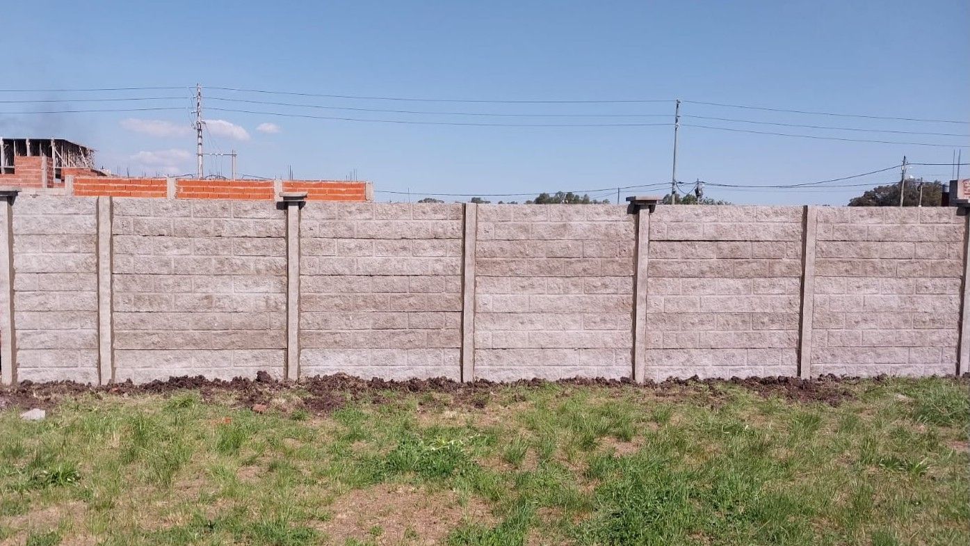 Una valla de hormigón está en medio de un campo de hierba.