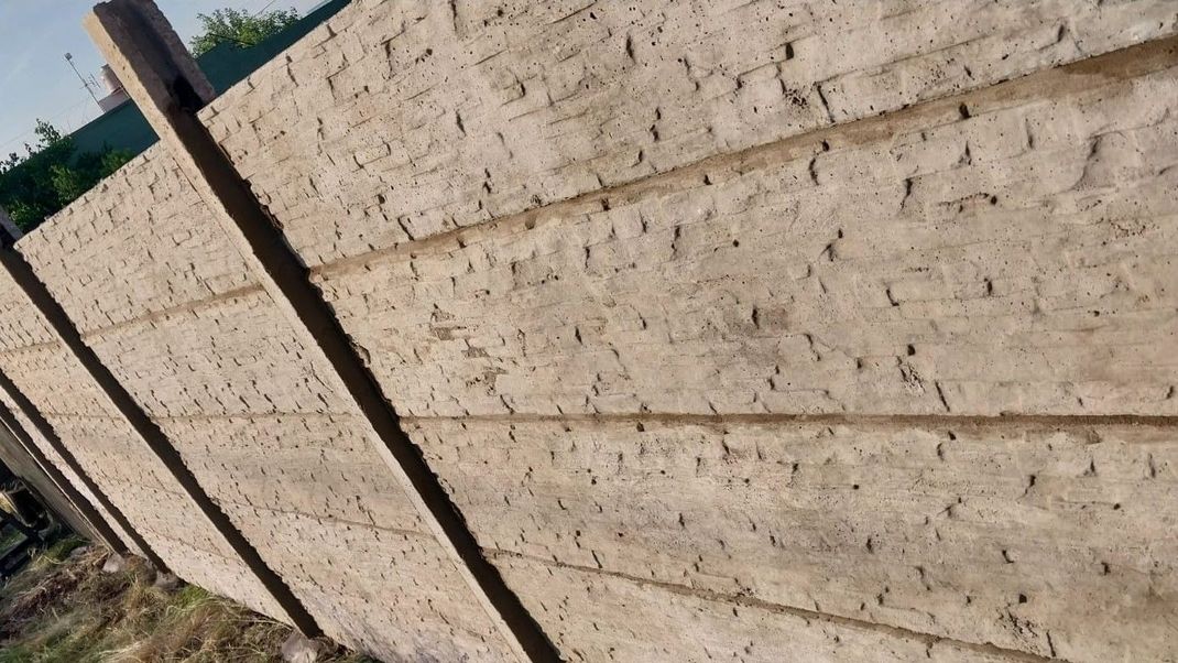 Un primer plano de una valla de hormigón con postes de madera.