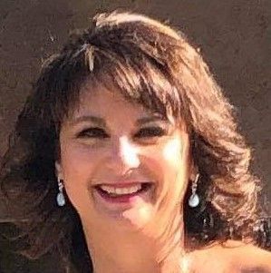 A woman with brown hair and earrings is smiling for the camera.