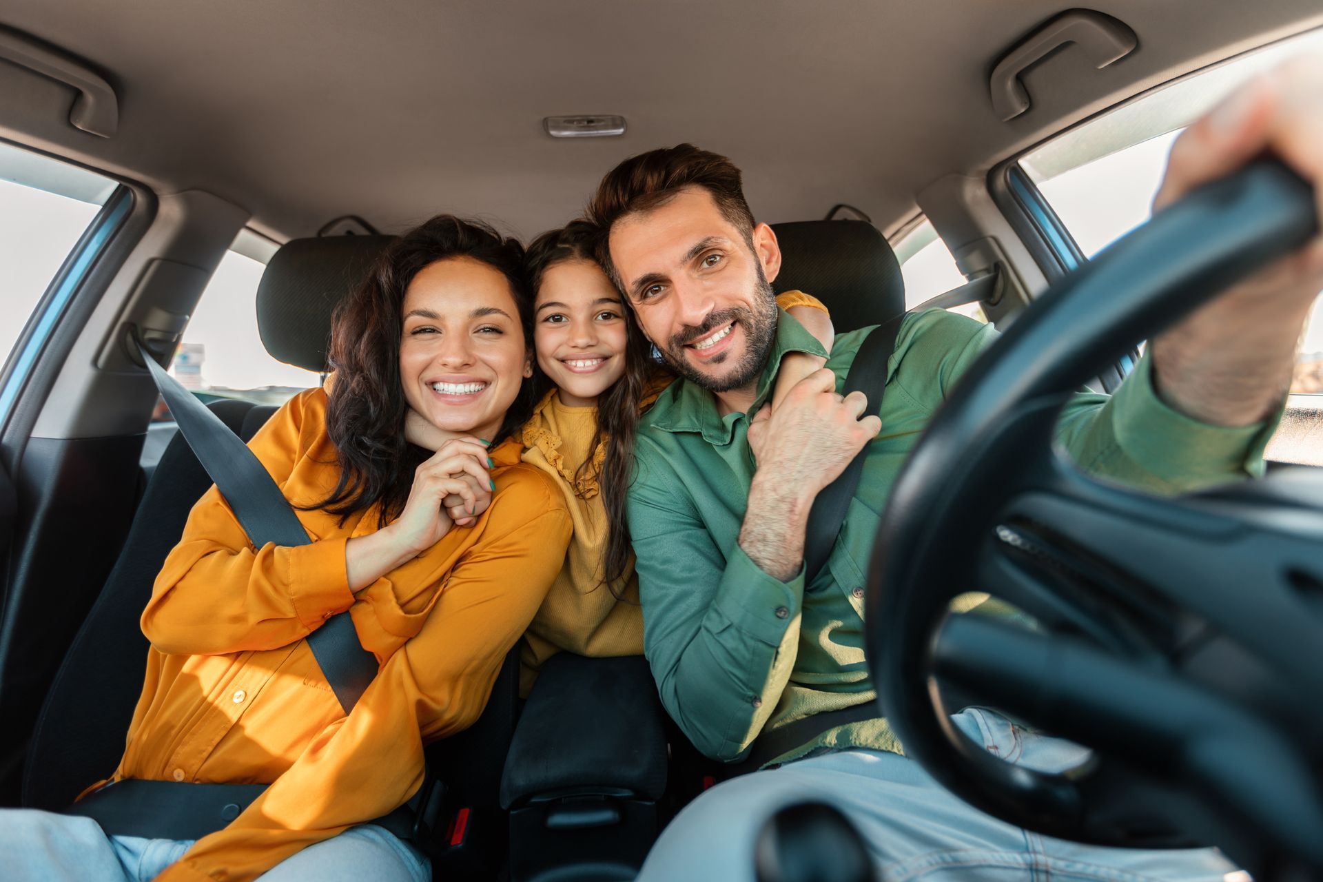A family is sitting in the back seat of a car.