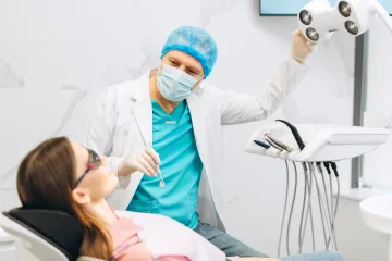 A dentist is examining a patient 's teeth in a dental office.