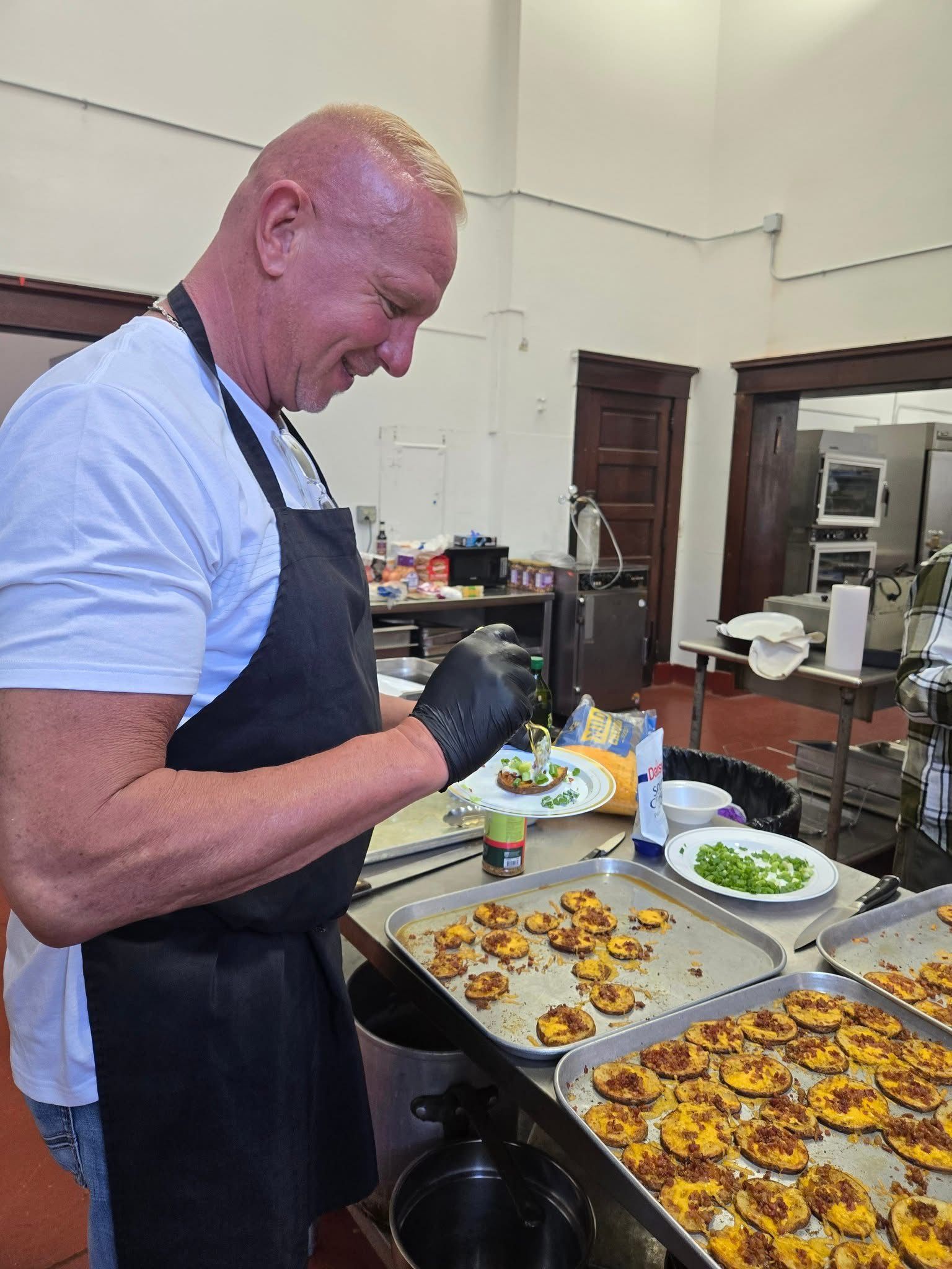 Man in black apron prepares food in a kitchen.