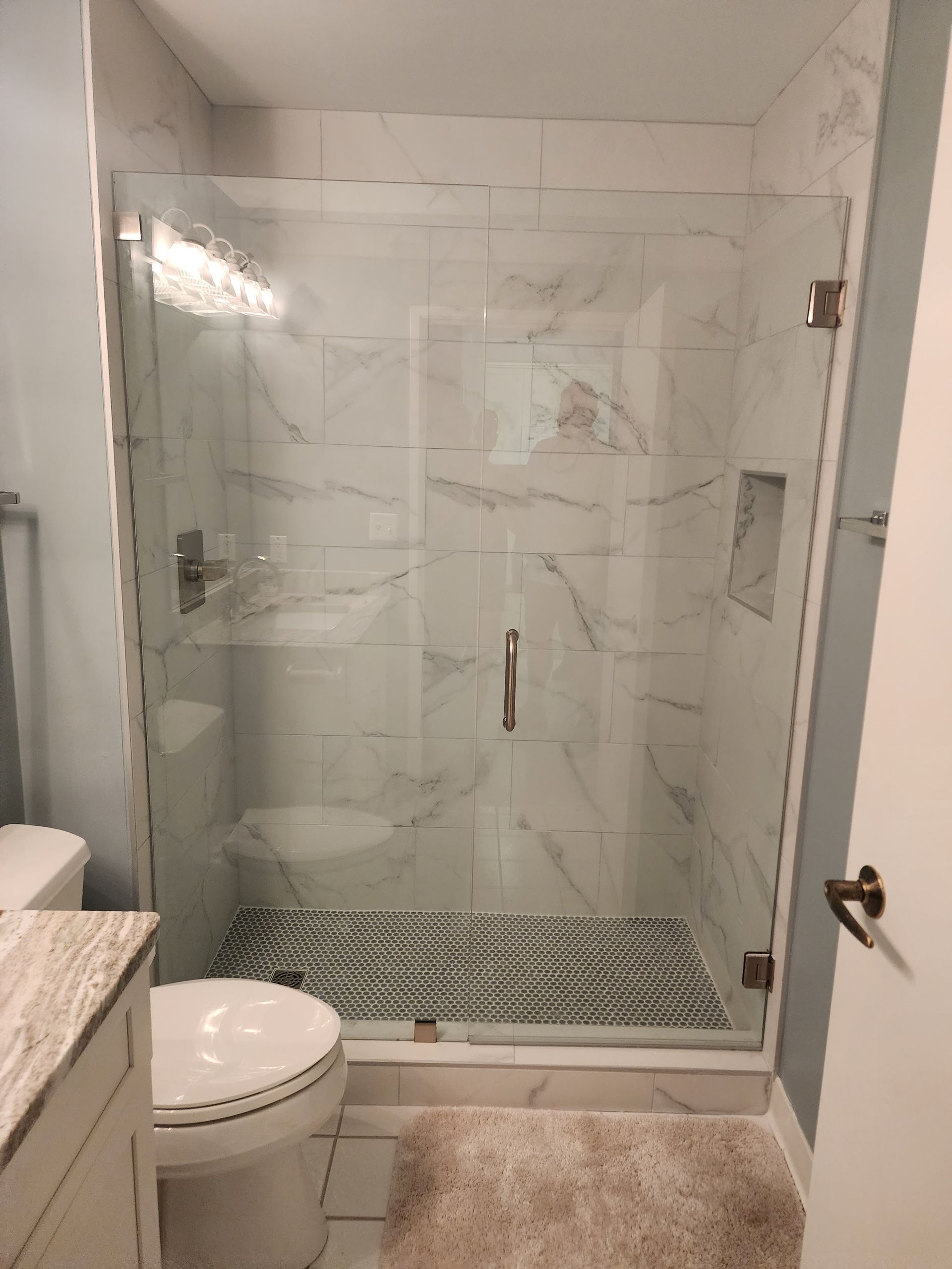 Bathroom with glass-enclosed walk-in shower, toilet, and marble tile floor