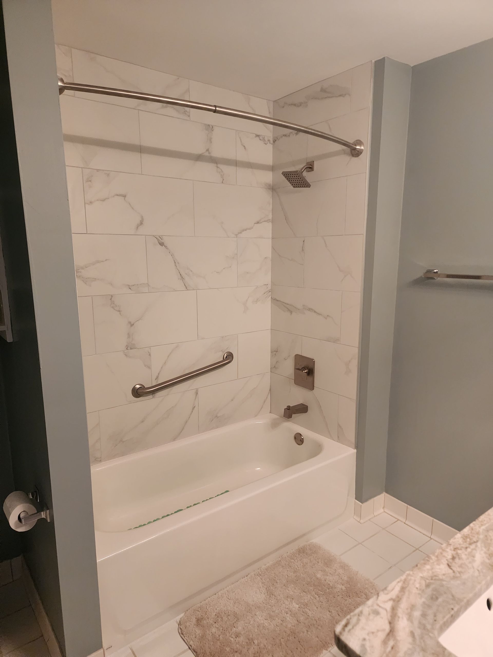 Accessible bathroom with a walk-in tub, grab bars, and shower curtain rail near a sink and towel rack
