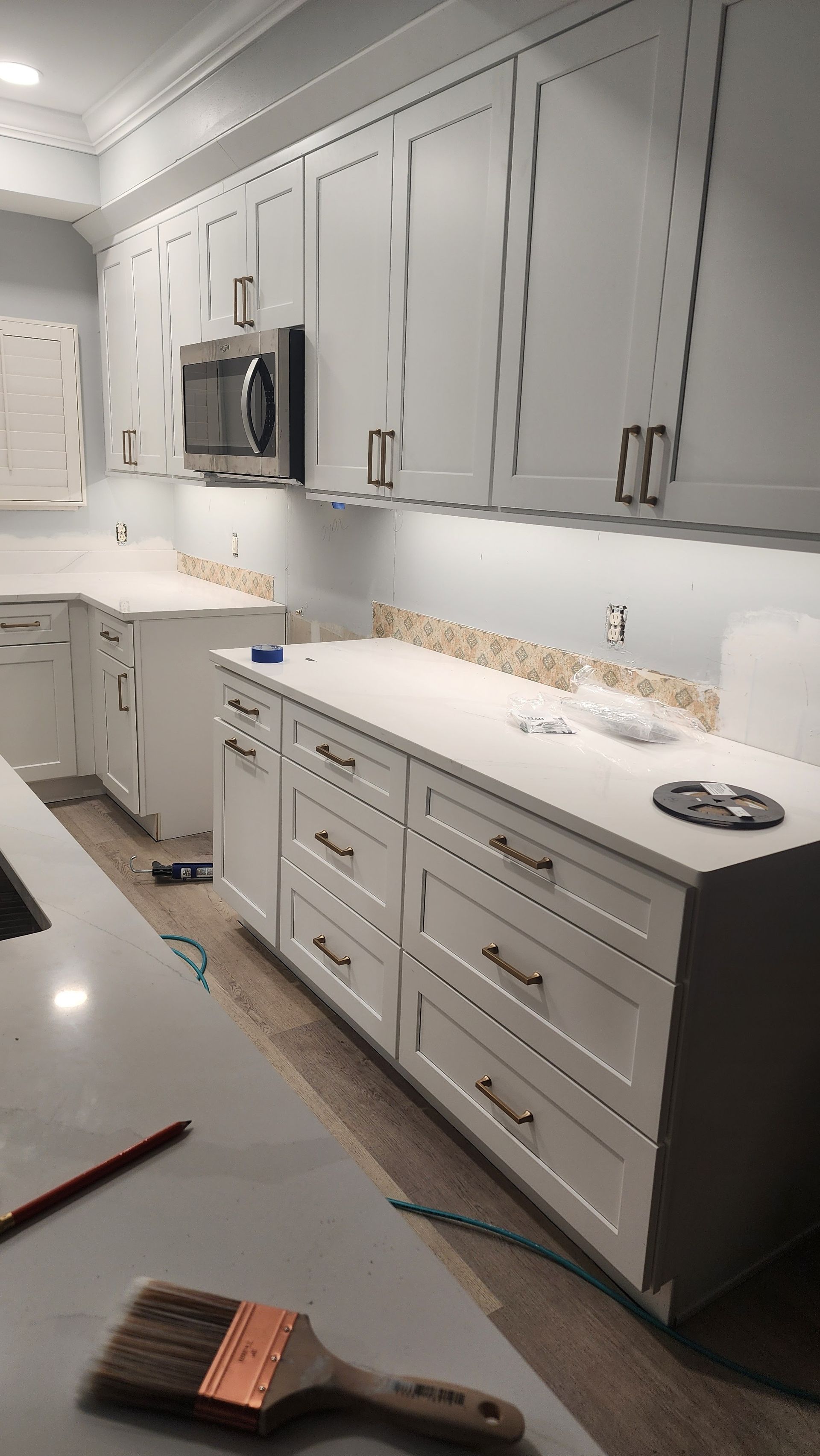 Modern kitchen with gray cabinets, white countertops, and a built-in microwave.