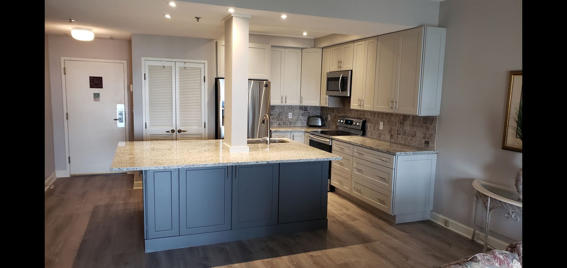 Modern kitchen with gray island, white cabinets, stainless appliances, and wood floors