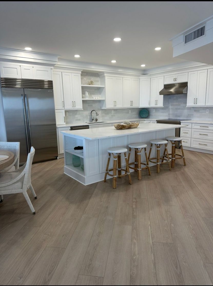 Modern kitchen with gray island, white cabinets, stainless appliances, and wood floors