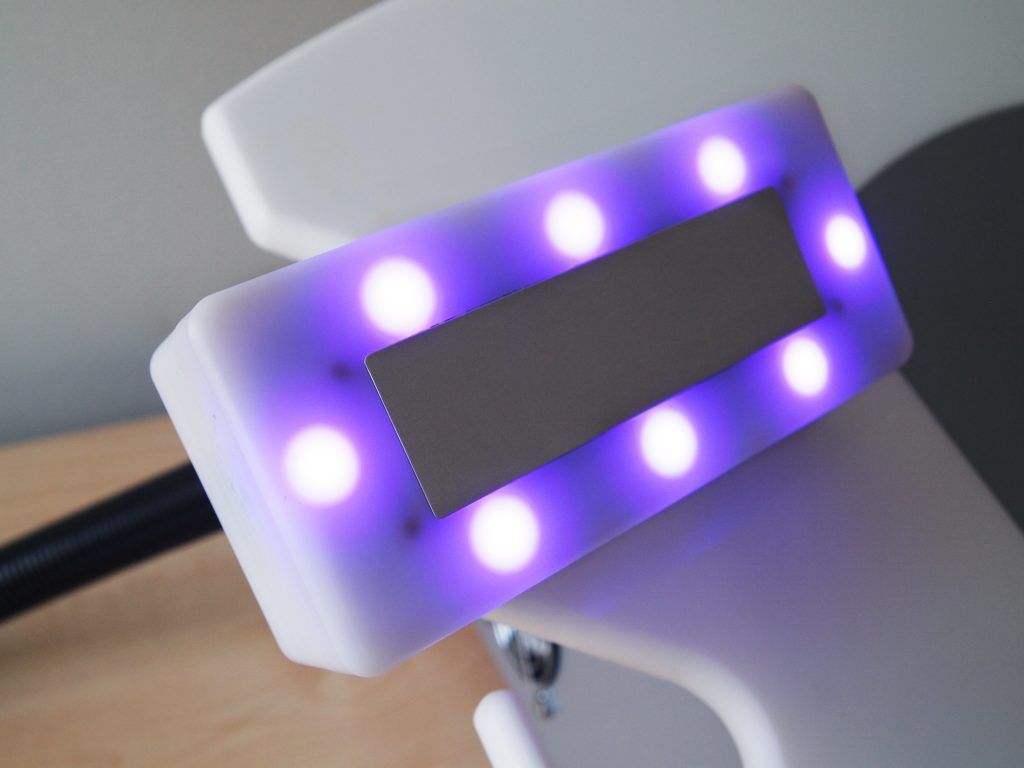 Close-up of a Waves 21 handpiece with glowing purple LED lights – part of multi-frequency treatment technology.