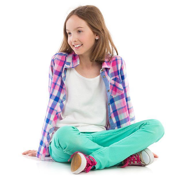 A little girl is sitting on the floor with her legs crossed.